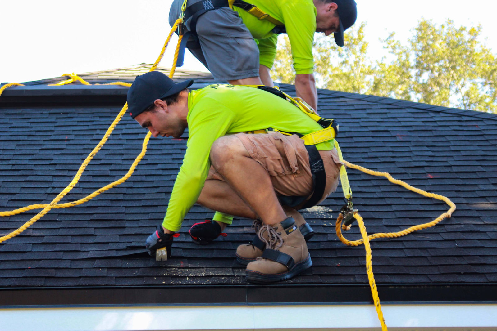 Roofing crew fastening shingles on a residential roof